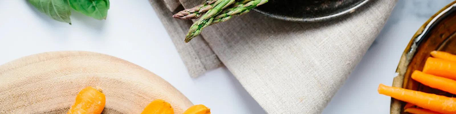 Grüner Spargel und frische Möhren auf einem Holzbrett