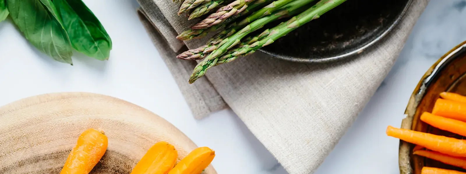 Grüner Spargel und frische Möhren auf einem Holzbrett