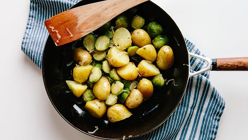 Rosenkohl und Kartoffeln mit Schale werden in einer Pfanne angebraten