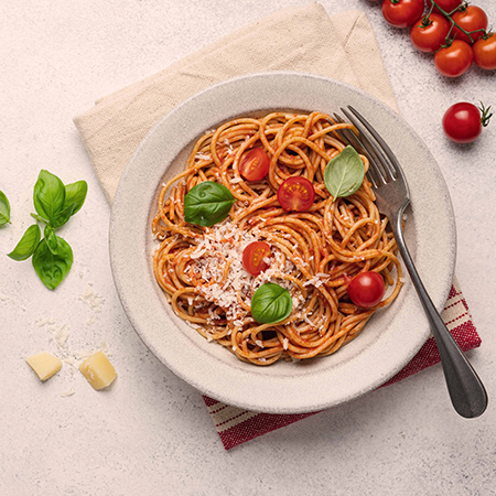 Spaghetti in Tomatensoße mit Basilikum auf einem weißen Teller