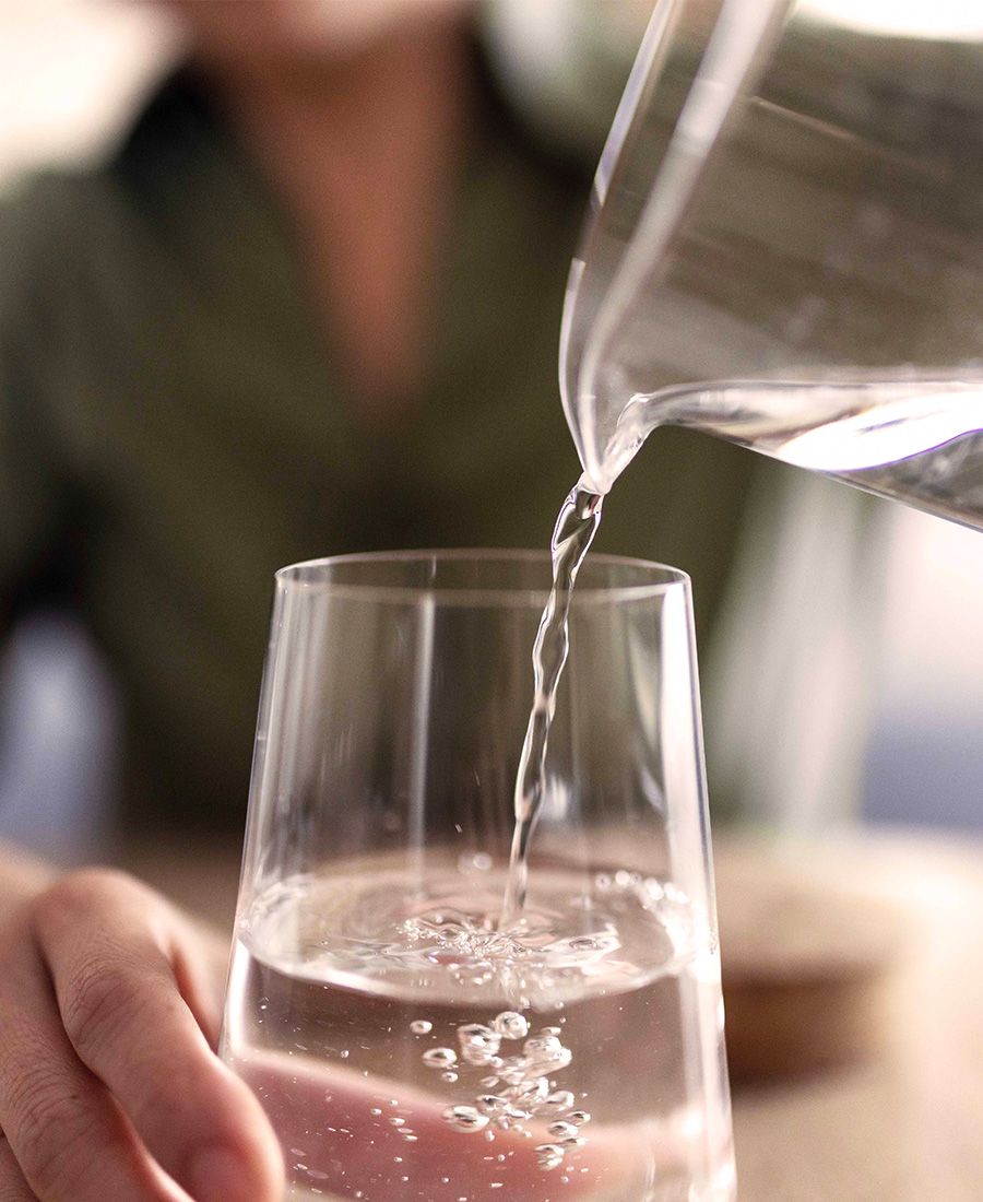 Aus der Karaffe fließt Wasser in ein Glas