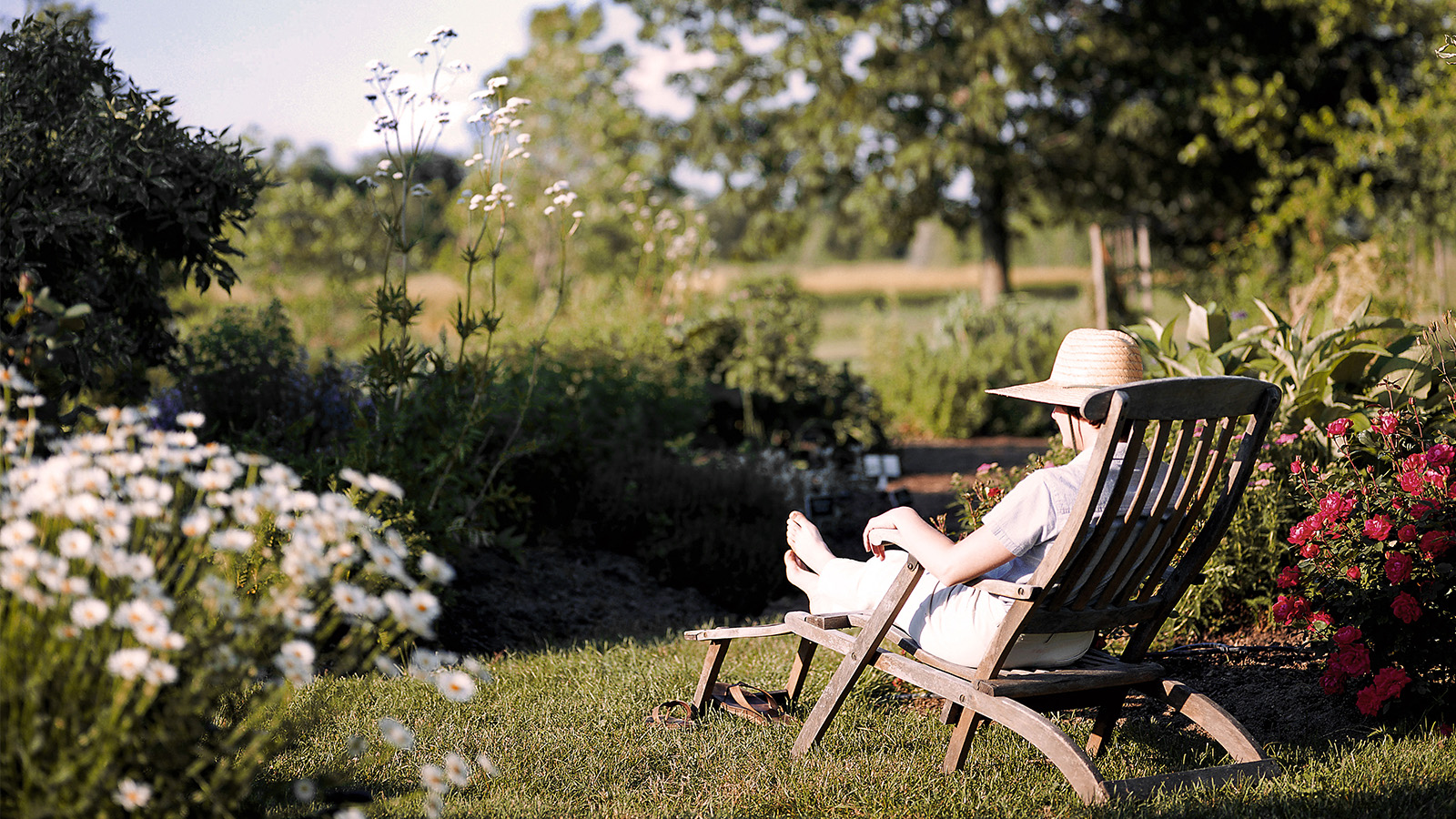 Ältere Frau sitzt im Garten auf dem Sonnenstuhl