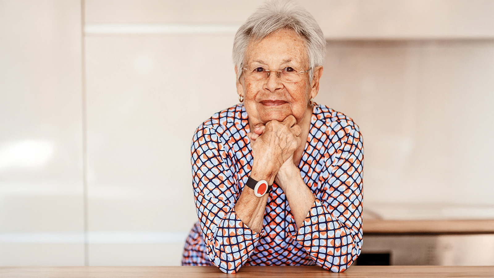 Seniorin in der Küche mit einem Notruf Armband am Handgelenk