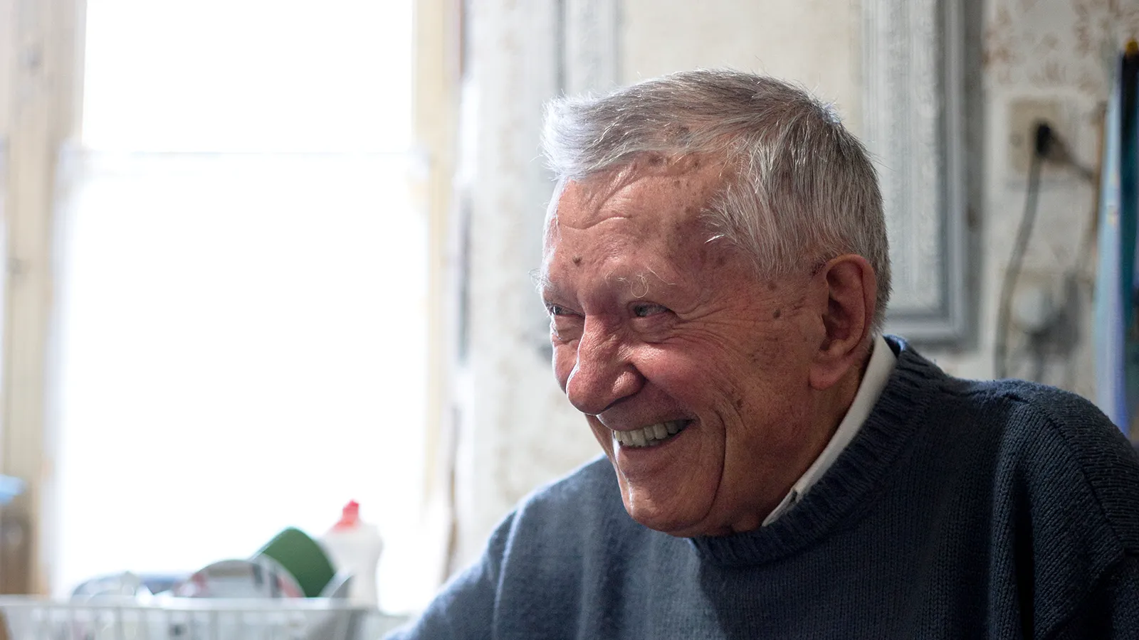 Mann sitzt lachend in der Küche am Esstisch