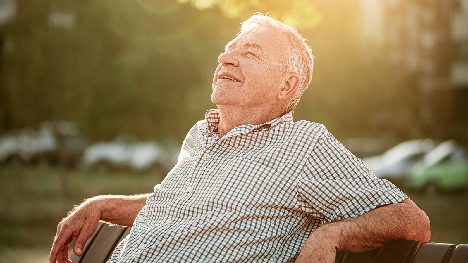 Senior sitzt auf der Bank im Park und sonnt sich