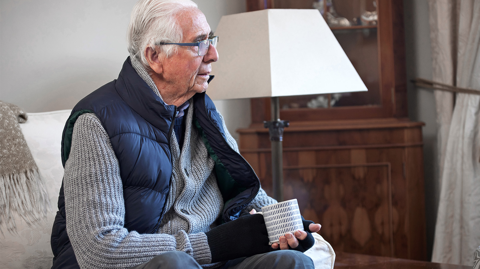 Senior trinkt einen heißes Getränk im Wohnzimmer