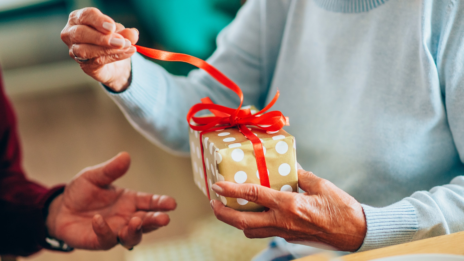 Frau oeffnet die Schleife von einem kleinen Geschenk