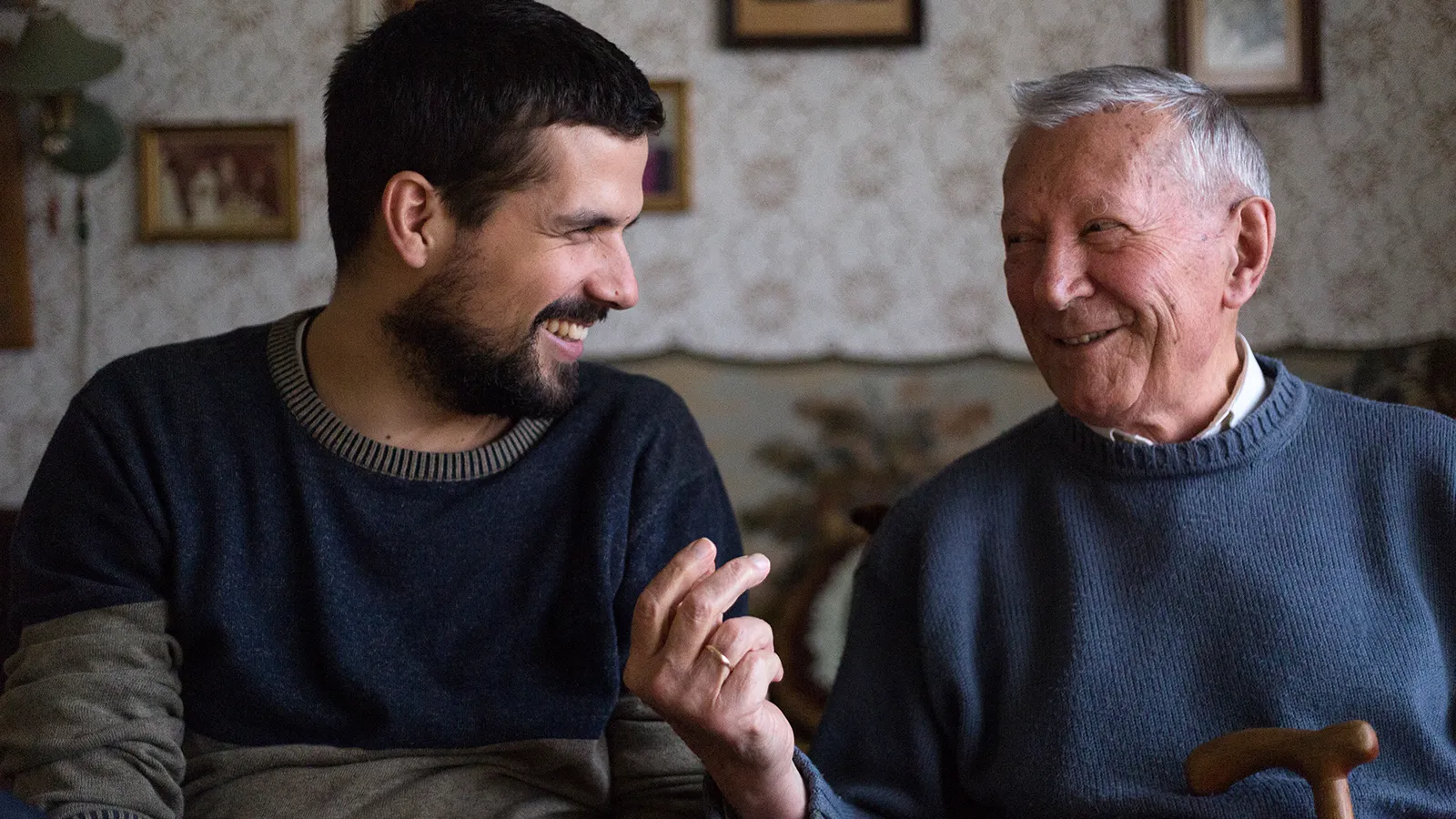 Vater und Sohn unterhalten sich fröhlich im Wohnzimmer