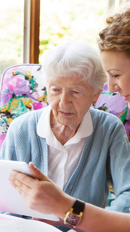 Frau mit grauen Haaren und Ihre Tochter schauen sich zusammen etwas auf dem Computer an