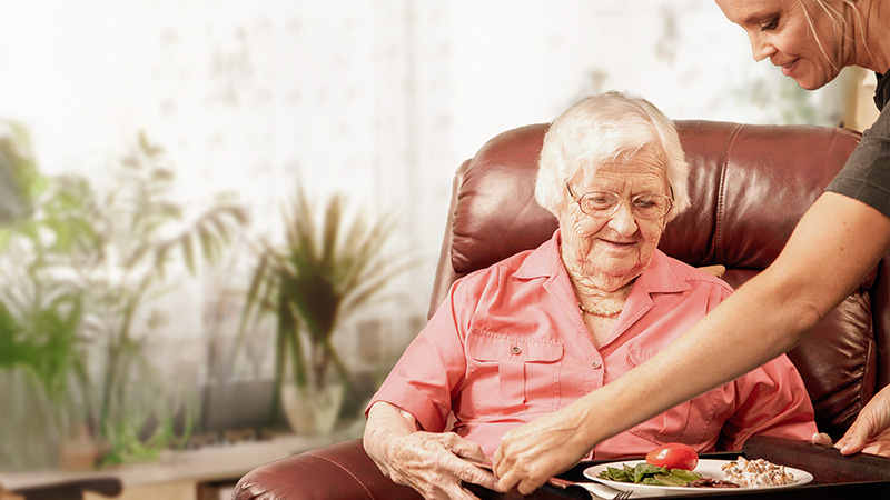 Seniorin bekommt ein Mittagessen serviert