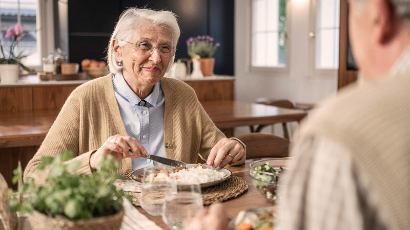 Eine Mitarbeiterin blickt in das Gewächshaus mit langen Reihen von frischem Salat