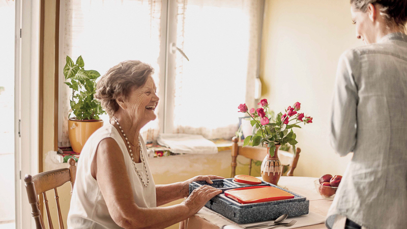 ältere Frau bekommt ihr Mittagessen in einer Isolierbox gebracht