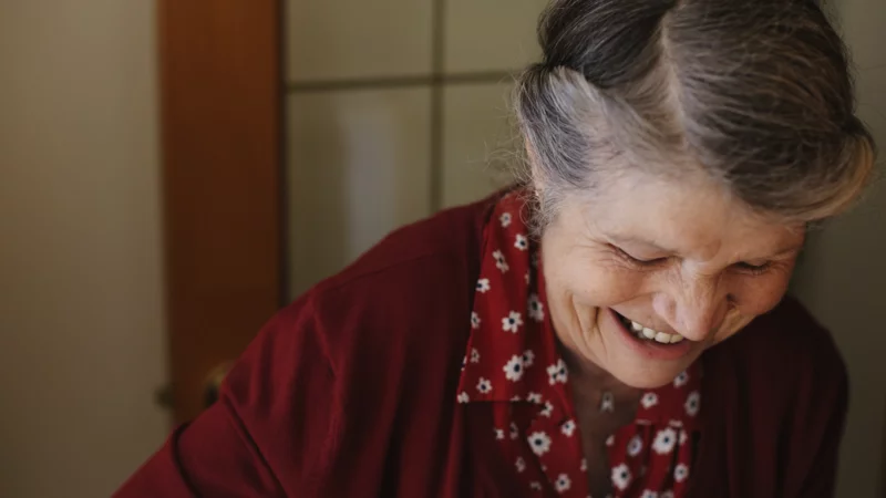 Lächelnde Seniorin in roter Strickjacke