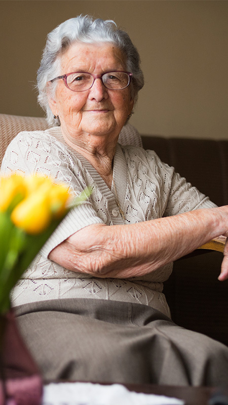 Ältere Dame sitzt erwartungsfroh im Sessel