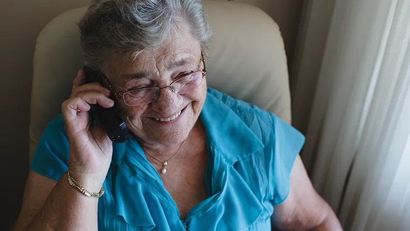 Eine Frau mit grauen Haaren telefoniert und lächelt